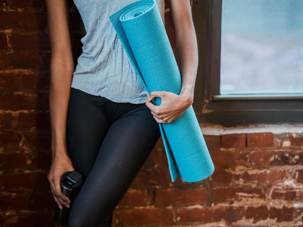 A neatly rolled yoga mat next to a water bottle in a calm room.